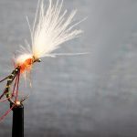 Hopper fly tying pattern in olive, orange, and brown on gray background